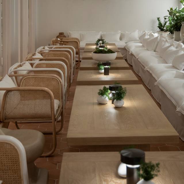 Looking down the long tables in the Conservatory with wooden tables and white seating at Lyle DC.