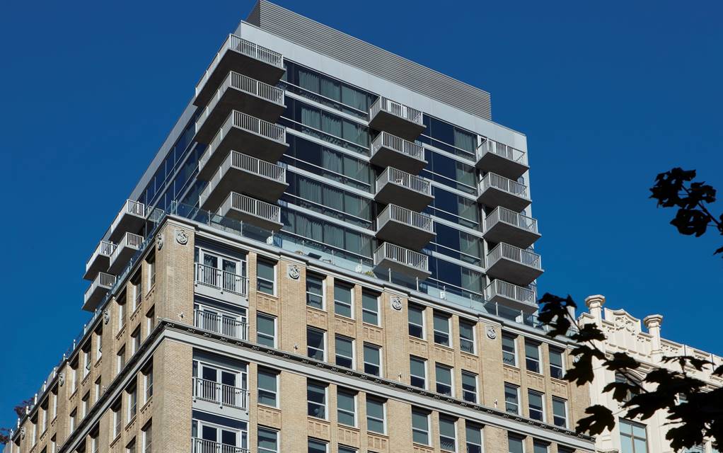 Modern upper floors of the Hotel Park Ave NYC in contrast with its historic stone base.