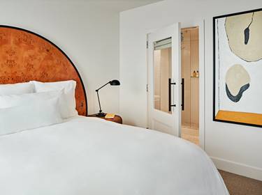 A Premier King Room at Lyle DC, featuring a king-size bed, and stylish artwork.