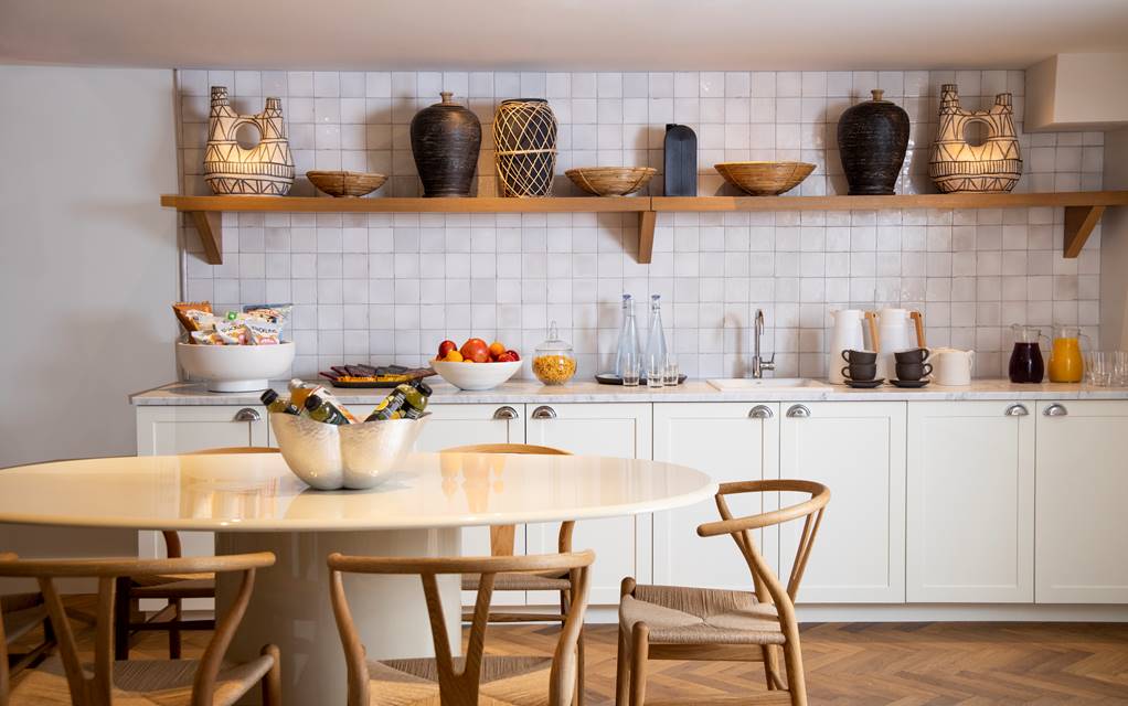 The Pantry kitchen with a wooden table and white wall tiles.